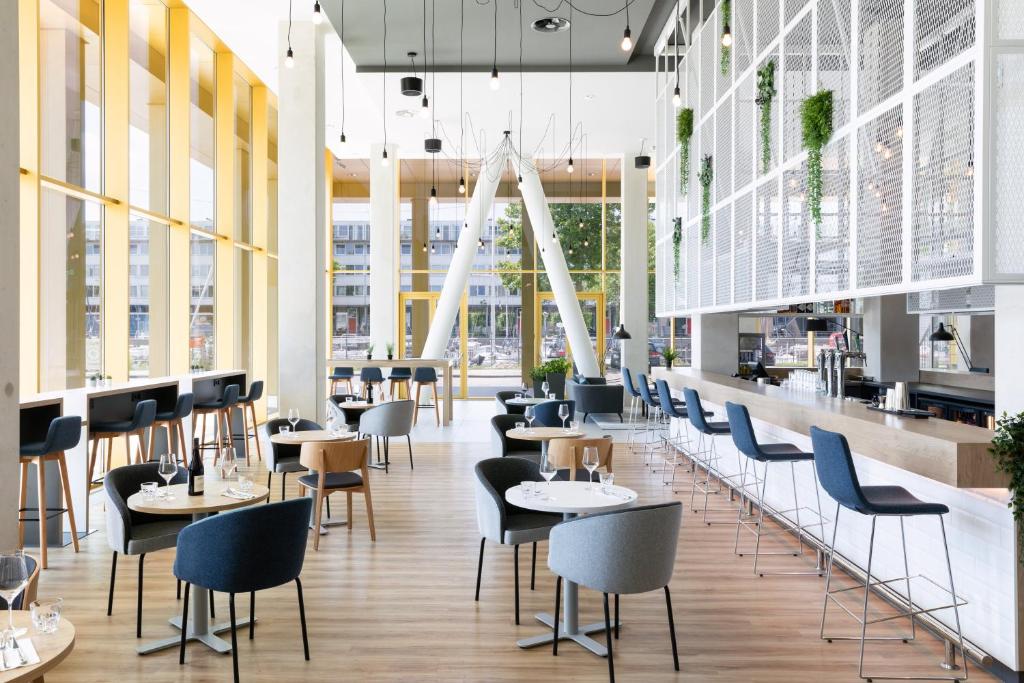 a restaurant with tables and chairs and windows at Holiday Inn Express Amsterdam - North Riverside by IHG in Amsterdam