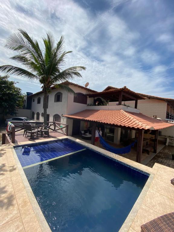 a pool in front of a house with a palm tree at Casa das Dunas in Tamoios