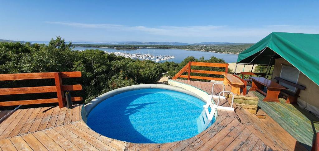 a swimming pool on a deck with a view of a river at MARUŠINA OLIVE HILLS - glamping & minicamp in Punat