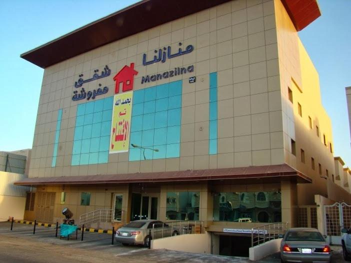 a large building with cars parked in front of it at Manazilna Apartments Riyadh منازلنا للشقق المفروشة in Riyadh