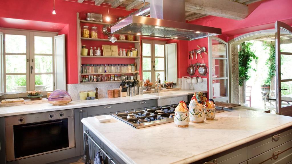 聖卡夏諾德伊巴尼的住宿－Casa Fabbrini Agriturismo，厨房设有红色的墙壁和炉灶。 顶部烤箱