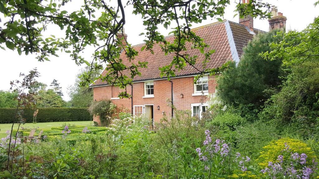 ein Backsteinhaus mit Garten davor in der Unterkunft Dairy Cottage Luxury B&B in Attleborough