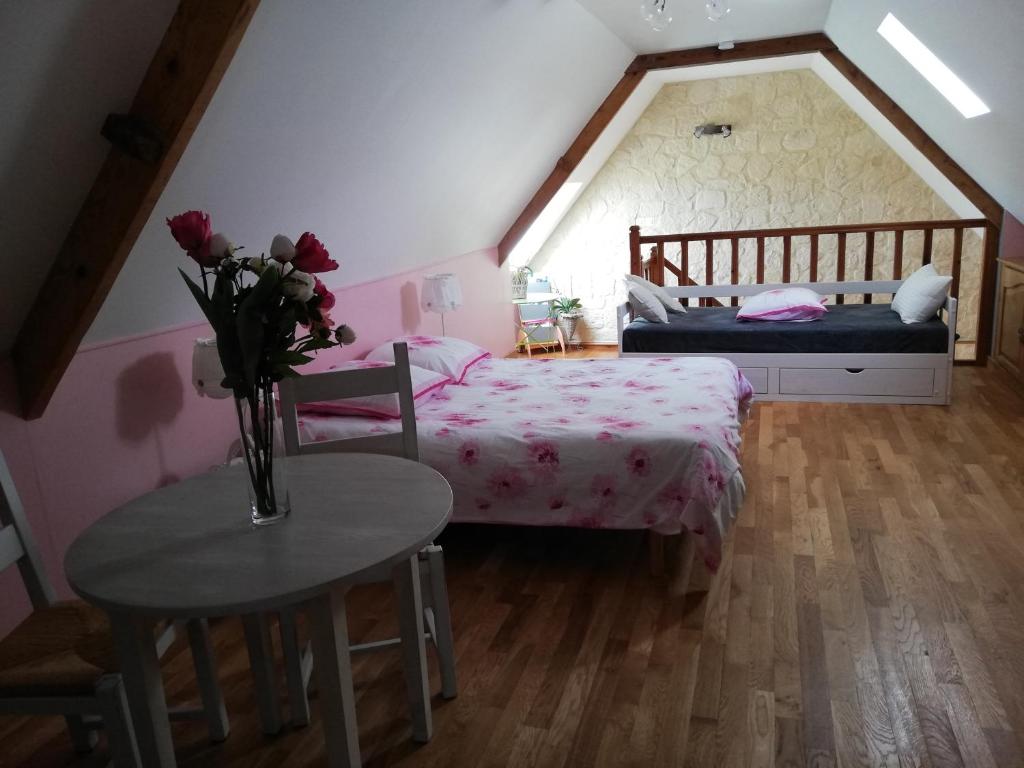 a bedroom with a bed and a table with a vase of flowers at les alouettes in Leschelles