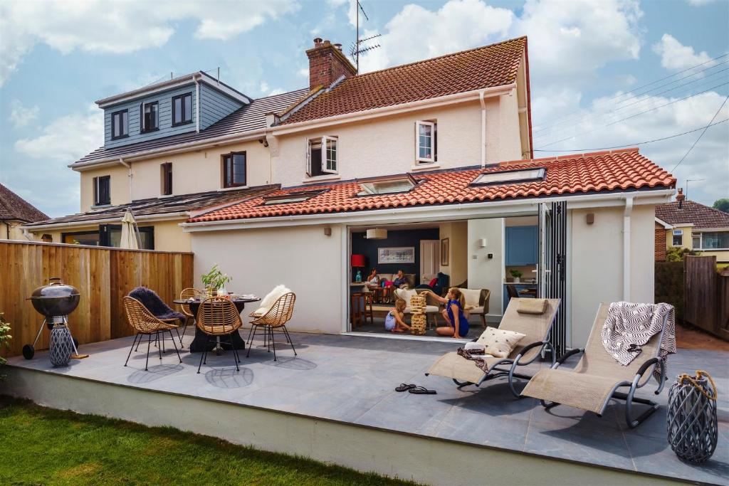a patio with chairs and a table in front of a house at Littlefields - Stylish, Modern Cottage With Large Garden, Close To Beach in Seaton