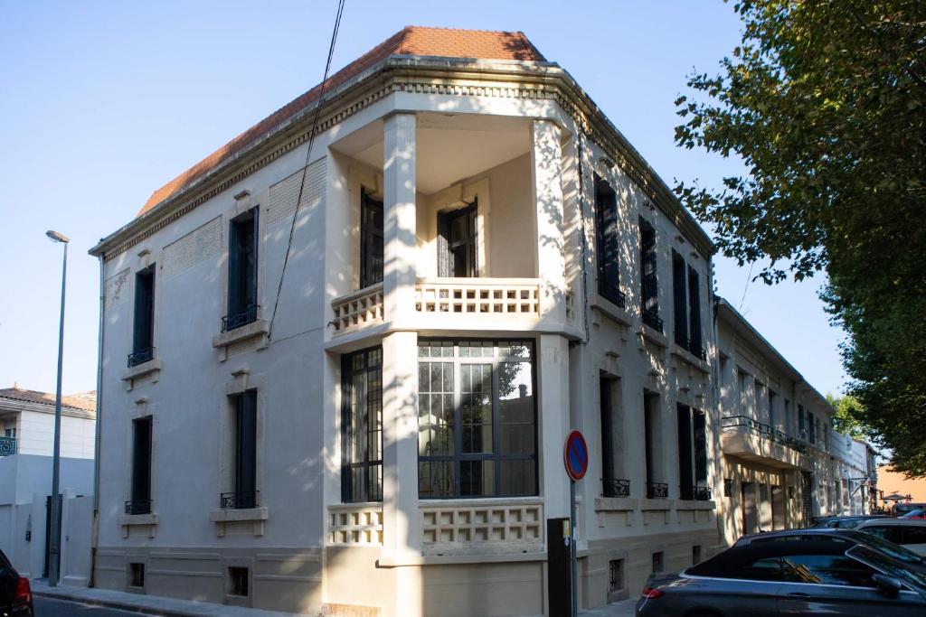 um edifício branco com uma varanda numa rua em Hotel Galla Placidia em Narbonne