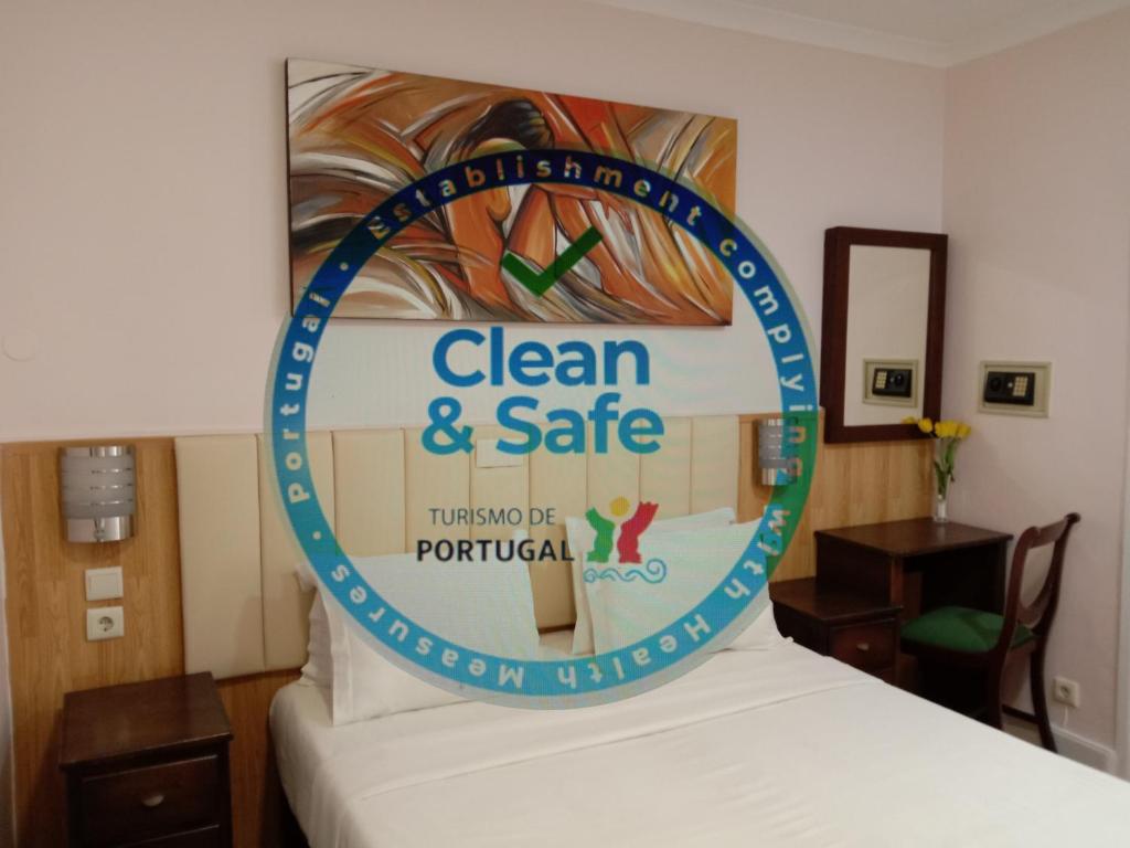 un cartel que dice limpio y seguro sentado en la parte superior de una cama en Faria Guimares Porto Centro en Oporto