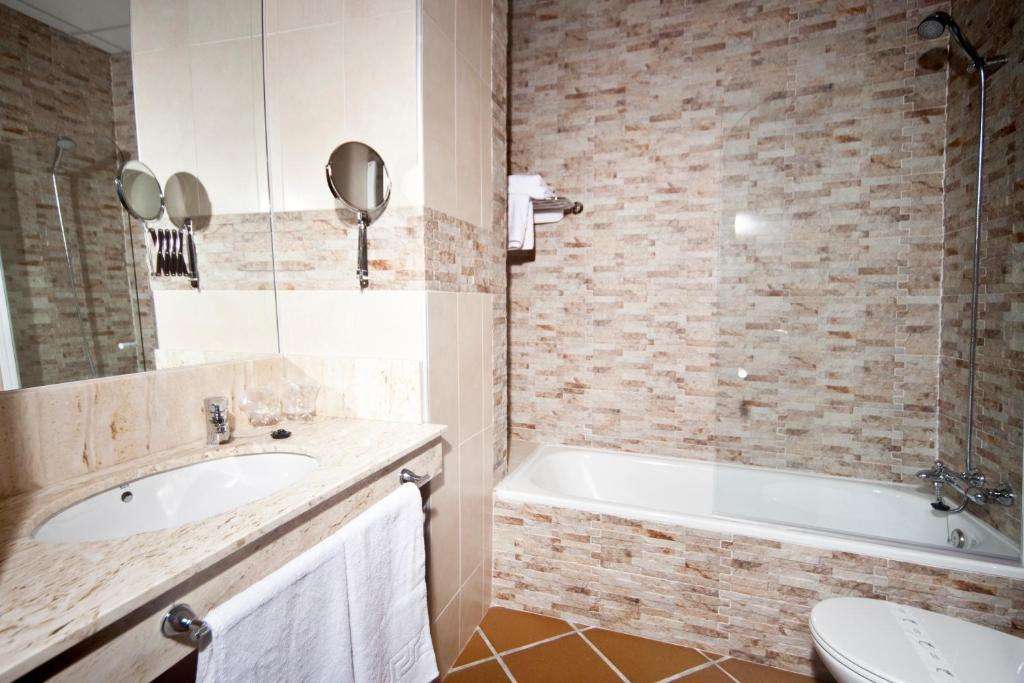 a bathroom with a tub and a sink and a toilet at Hotel Albaida Nature in Mazagón