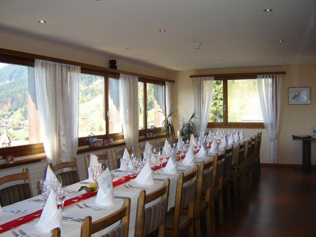 a room with a long table with chairs and windows at Hotel Fassbind Beausite in Beatenberg