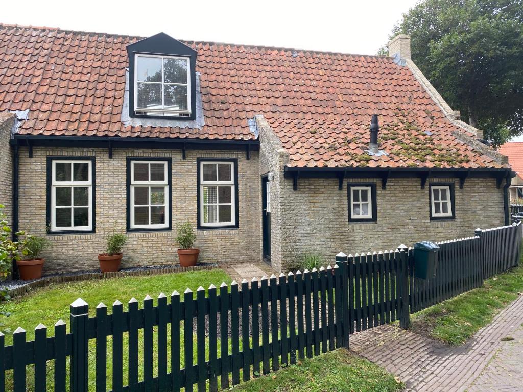 a small house with a black fence in front of it at Casa Vinke op Ameland in Hollum