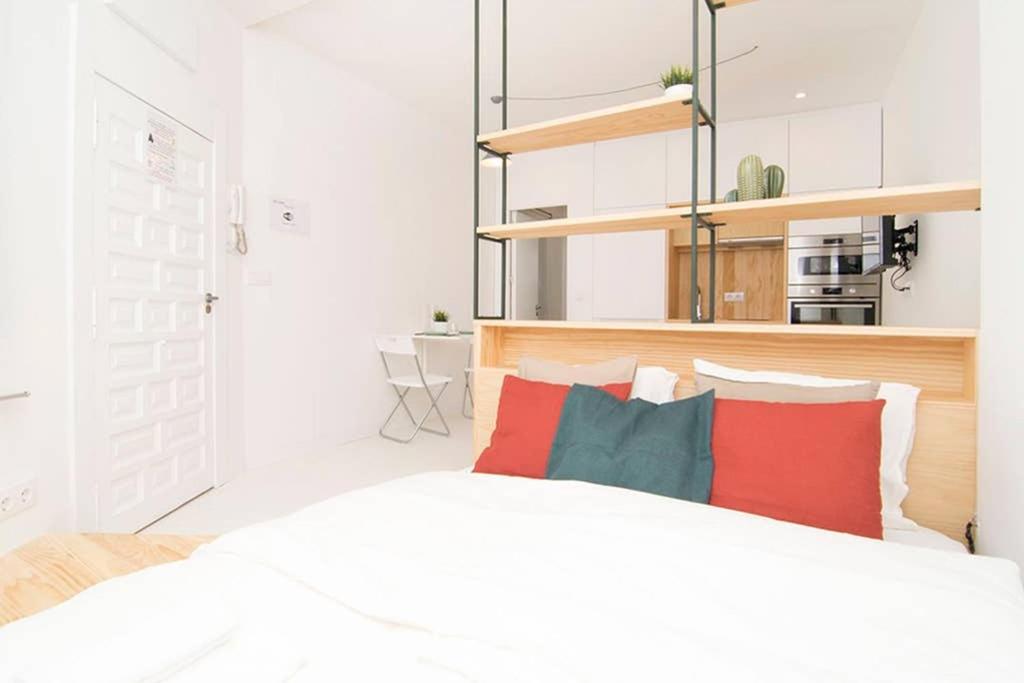 una camera da letto con un letto bianco con cuscini rossi e blu di Loft de Diseño en Pleno Centro de Madrid, Calle Torrecilla del Leal, by Batuecas a Madrid