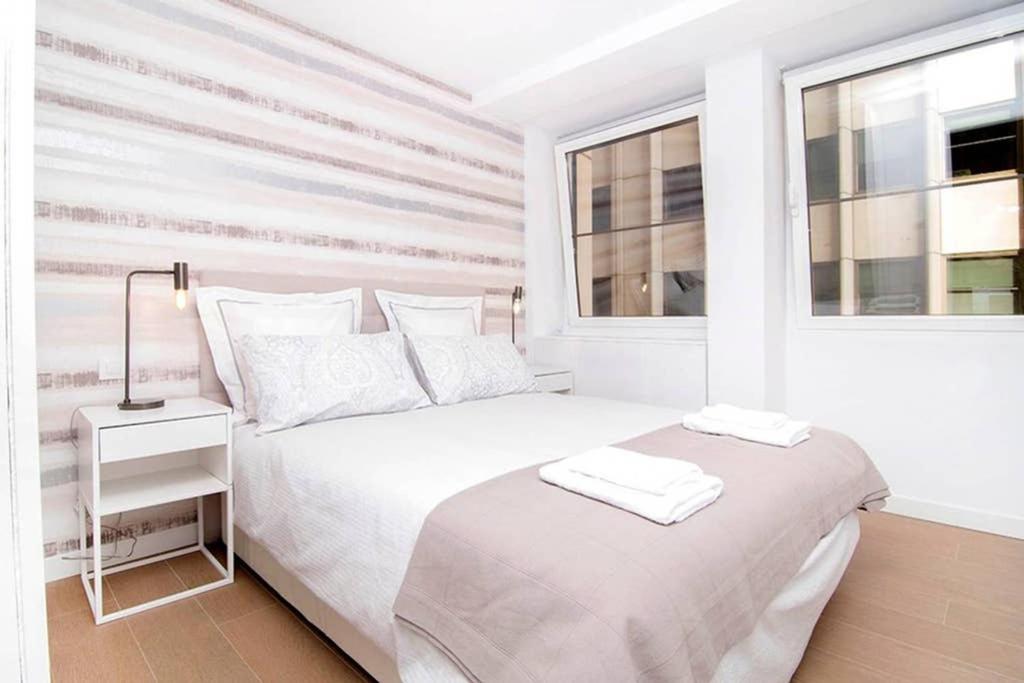 ein weißes Schlafzimmer mit einem weißen Bett und zwei Fenstern in der Unterkunft Deslumbrante Apartamento en Plaza España, by Batuecas in Madrid