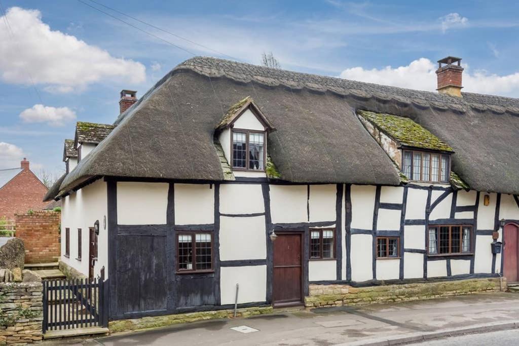 MickletonにあるCotswold Thatched Cottageの茅葺き屋根の白黒の古い建物