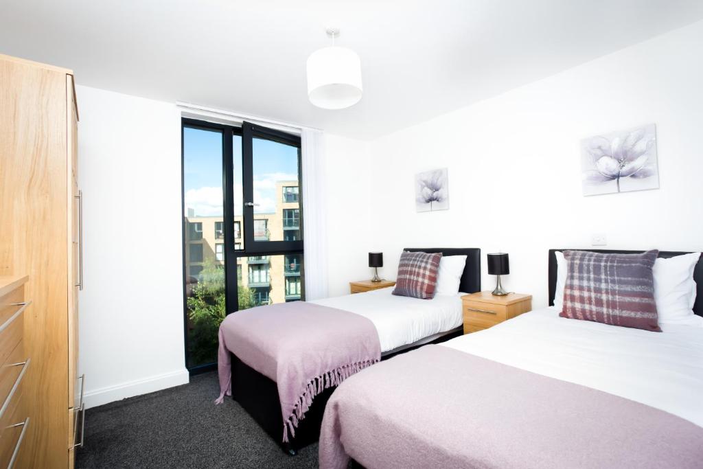 two beds in a room with a window at Absolute Stays on Essex - Chinatown - Hippodrome - Alexandra Theatre - Bull Ring - The Rep - B'Ham Intl Airport - Free WiFi - Free Parking - Contractors - Corporates in Birmingham