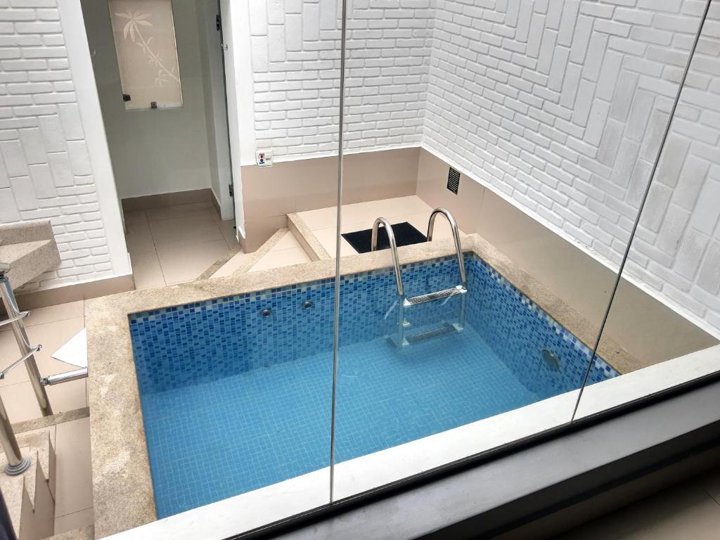 a bathroom with a large swimming pool with a shower at Motel Ilha de Capri in São Bernardo do Campo