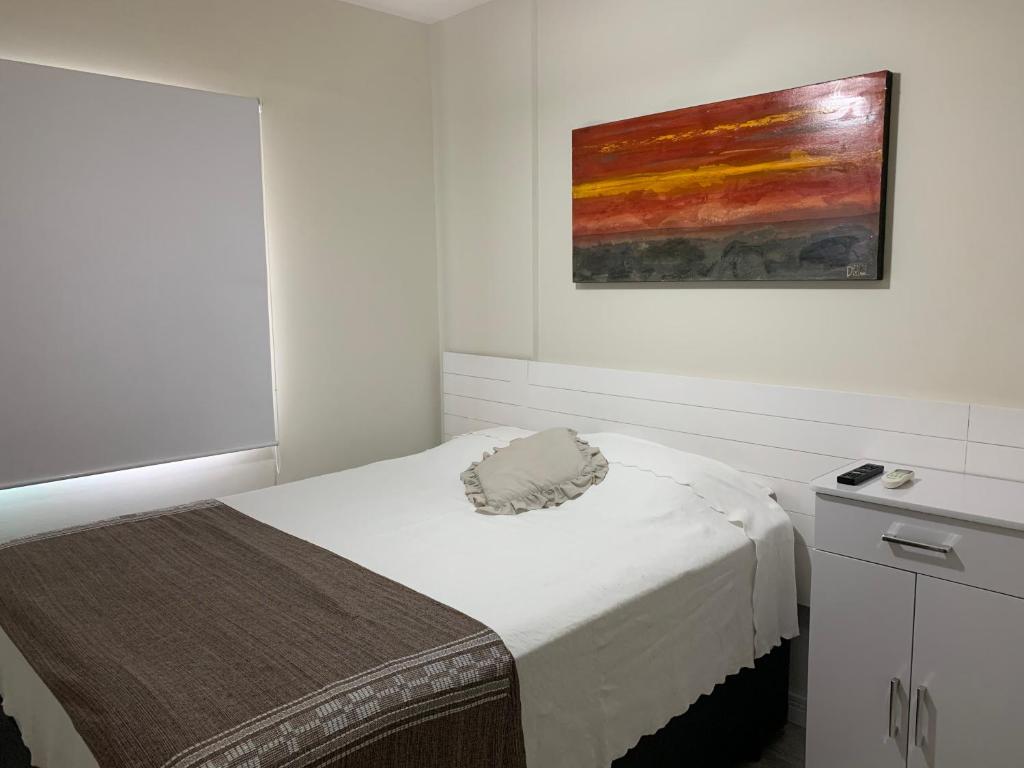 a bedroom with a bed and a painting on the wall at Boulevard Riviera Flat - Praia in Riviera de São Lourenço