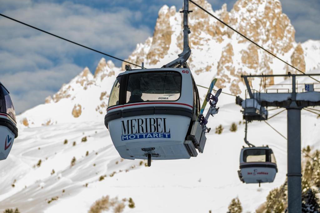 two gondolas on a ski lift over a snow covered mountain at Hôtel Alpen Ruitor in Méribel