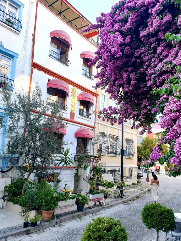 una donna che cammina lungo una strada davanti a un edificio con fiori viola di Oceans 7 Hotel a Istanbul