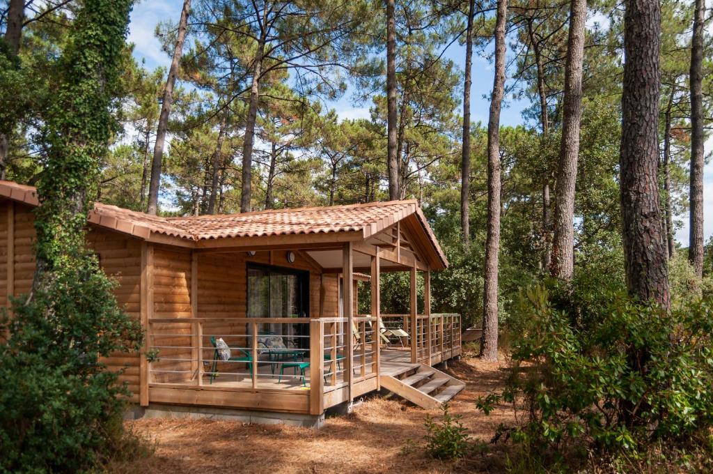 eine Blockhütte mit einer Veranda im Wald in der Unterkunft Chalet la lande in Ondres