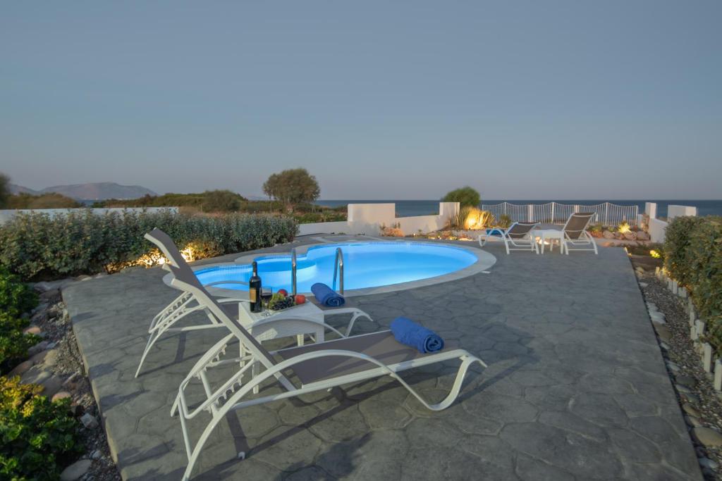 a swimming pool with chairs and a table at Aegiali Sea View Villa in Gennadi