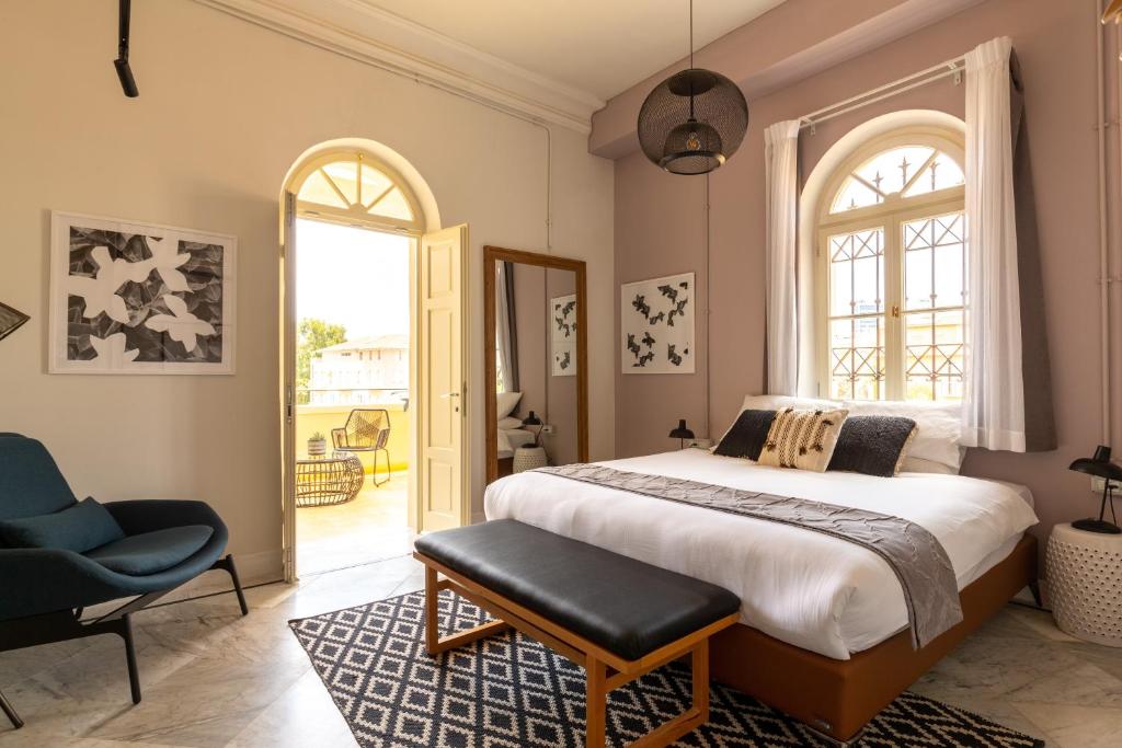 a bedroom with a bed and a chair and a window at Selina Neve Tzedek Tel Aviv in Tel Aviv
