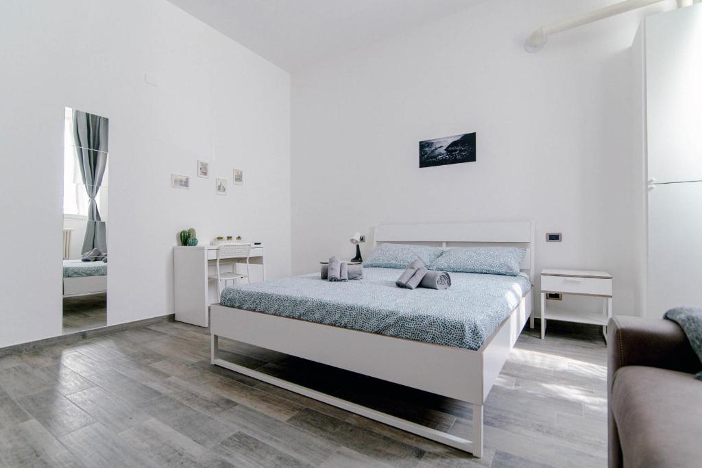 a white bedroom with a bed and a couch at Downtown Rooms in Como