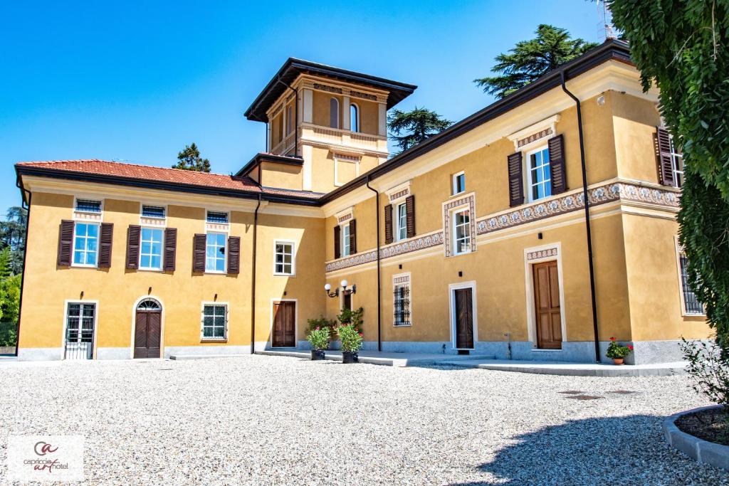 un gran edificio amarillo con una torre de reloj en la parte superior en Capriccio Art Hotel en Serravalle Scrivia