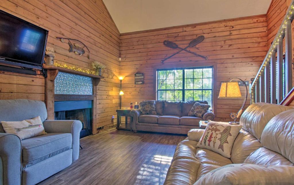 a living room with couches and a television in a cabin at Charming Branson Getaway with Fireplace and Porch in Branson