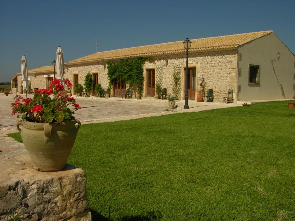 un edificio de piedra con una maceta de flores en la pared en Agriturismo Masseria sul Mare, en Avola