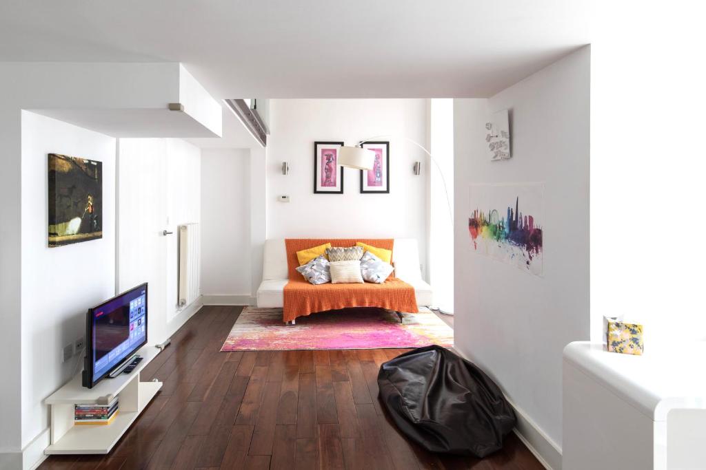 uma sala de estar com um sofá e uma televisão em My London Holiday Home em Woolwich