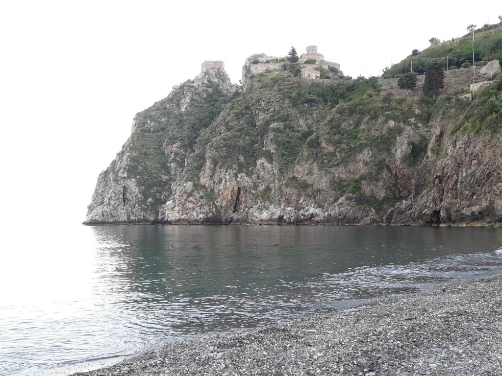 un castillo en una colina junto a un cuerpo de agua en Casa NUPI, en SantʼAlessio Siculo