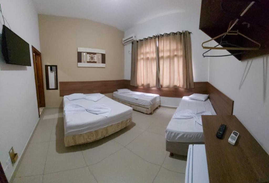 a hotel room with two beds and a table at Suites Santa Terezinha in Aparecida