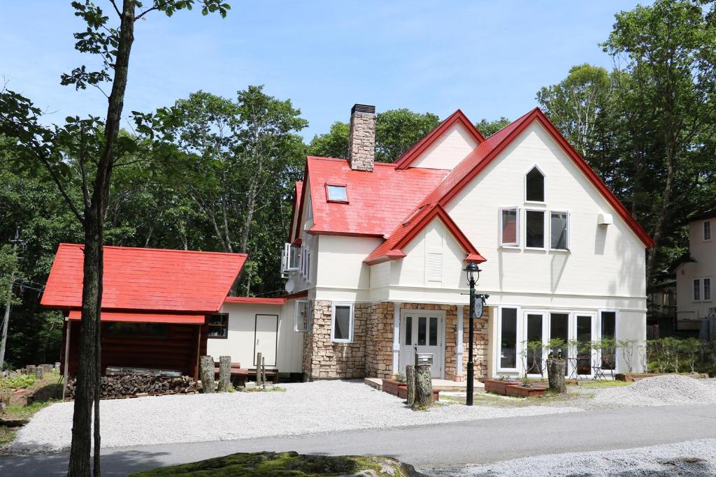 uma casa branca com um telhado vermelho em 白樺湖ペンションロック em Chino