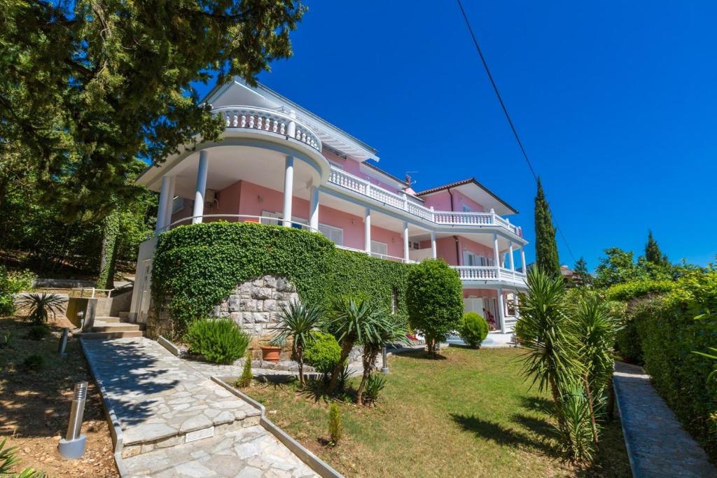 a large pink house with a green hedge at Two-Bedroom Apartment in Crikvenica XVIII in Sopaljska