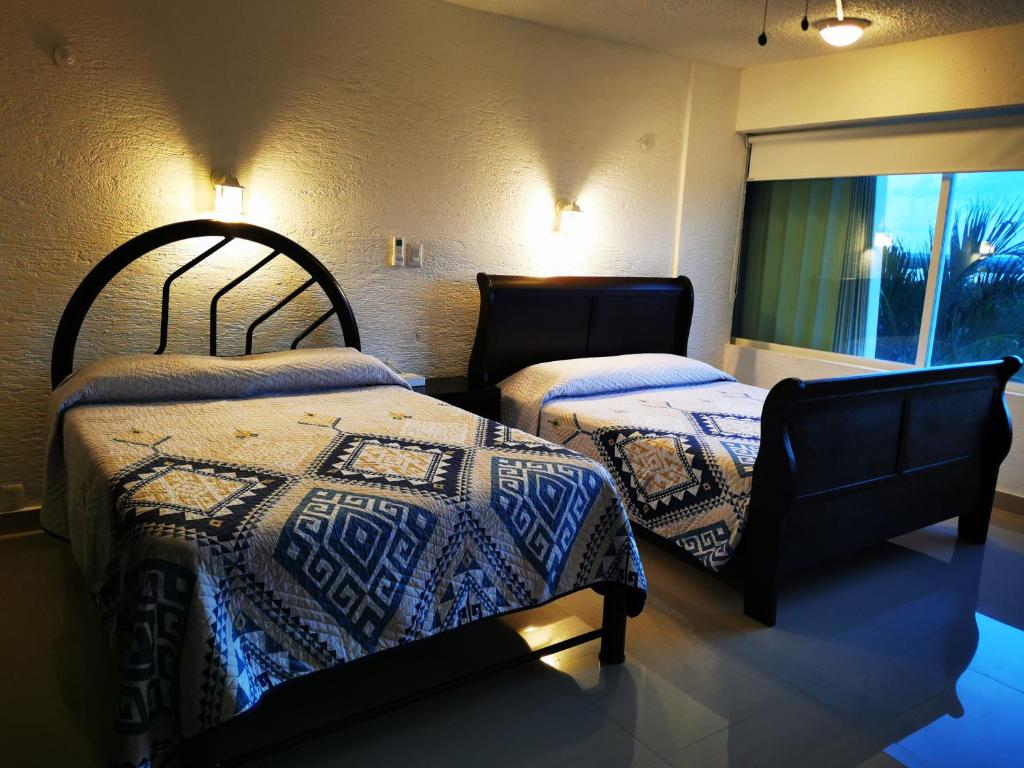 1 dormitorio con 2 camas y ventana en Suites Brisas Cancun, en Cancún