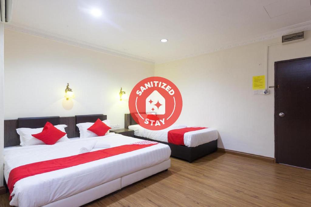 a hotel room with two beds and a sign on the wall at OYO 43915 T P Hotel in Sitiawan