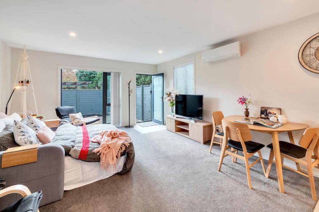 a living room with a bed and a table at Greenwich Townhouse with Parking and Air-Con in Auckland