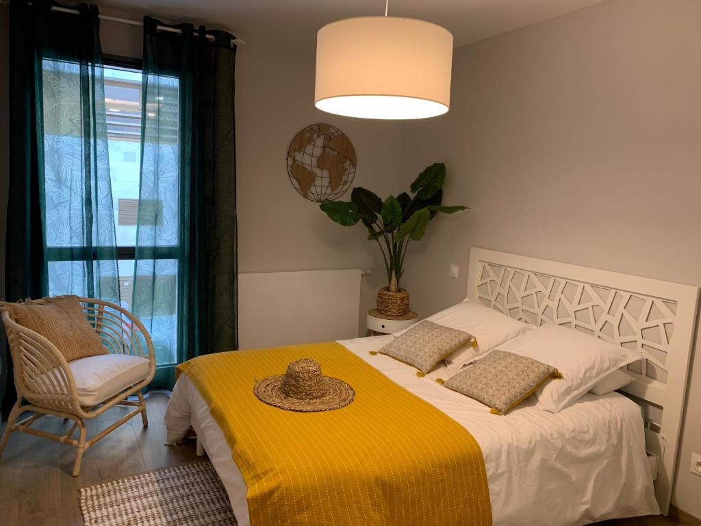 um quarto com uma cama com um cobertor amarelo e uma cadeira em Rodez Aveyron appart. T4 neuf 2 places parking em Rodez