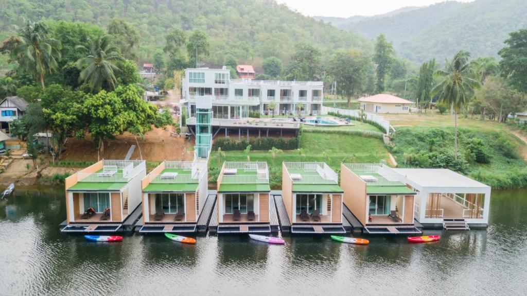 a group of houses on the water with boats at Erachon Raft Resort in Kanchanaburi City