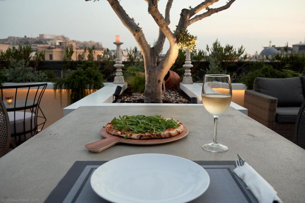 a table with a pizza and a glass of wine at Athens Mansion Luxury Suites in Athens