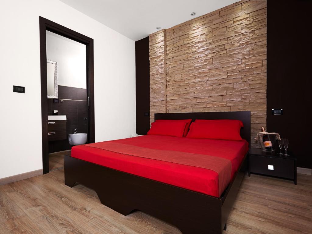 ein Schlafzimmer mit einem roten Bett mit Ziegelwand in der Unterkunft B&B La Bouganville in Alghero
