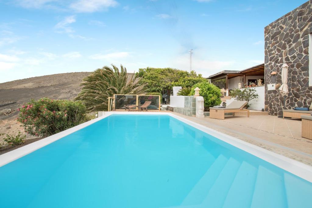 a large swimming pool with blue water in front of a house at Pure La Asomada in La Asomada
