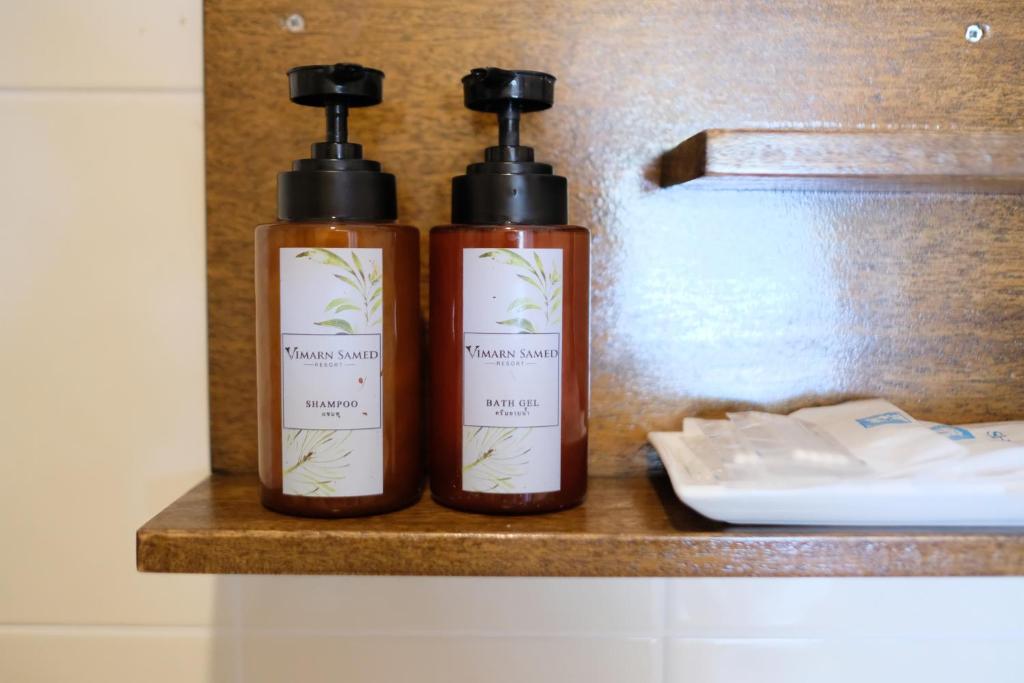 two bottles ofodorizers sitting on a shelf in a bathroom at Vimarn Samed Resort in Ko Samed