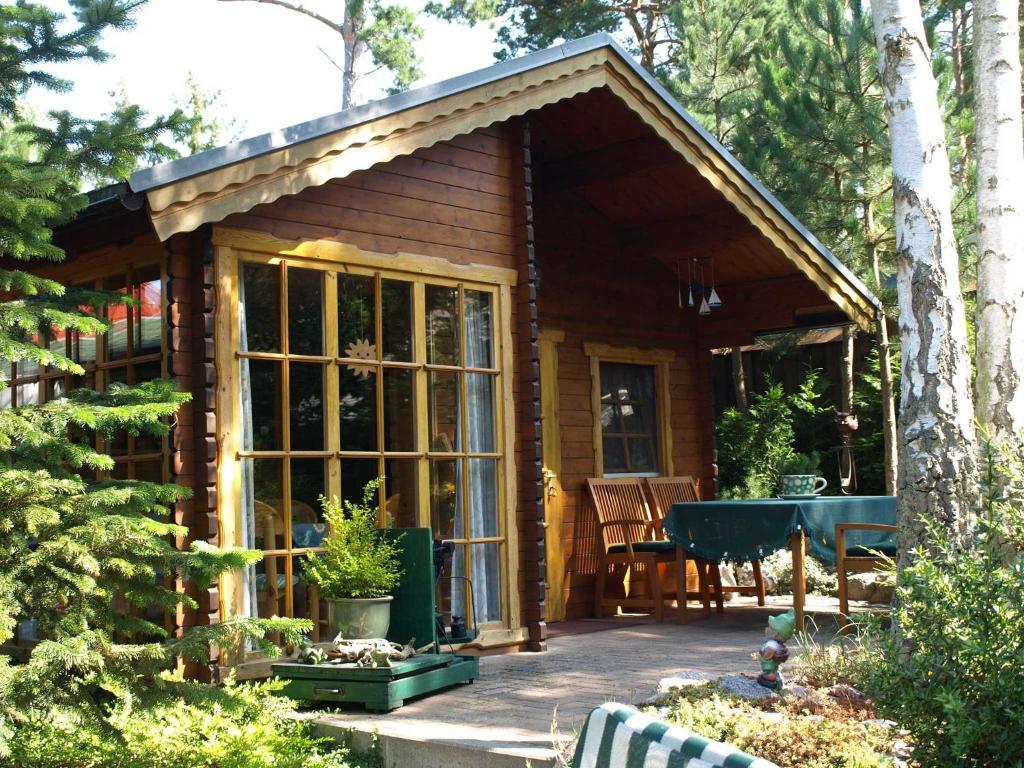 a small wooden cabin with a table in a garden at Blockhaus in Baabe - für 2 Erwachsene und 1 Kind von 5 bis 16 Jahre in Baabe