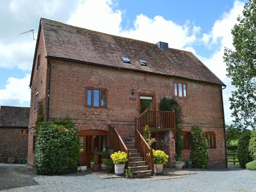 a brick house with a staircase in front of it at The Chaff House - farm stay apartment set within 135 acres in Bromyard