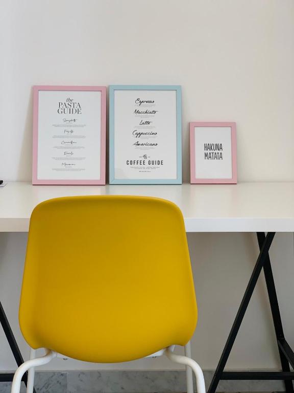 a yellow chair in front of a table with three pictures at AllYouCanTrip - La Nova in Naples