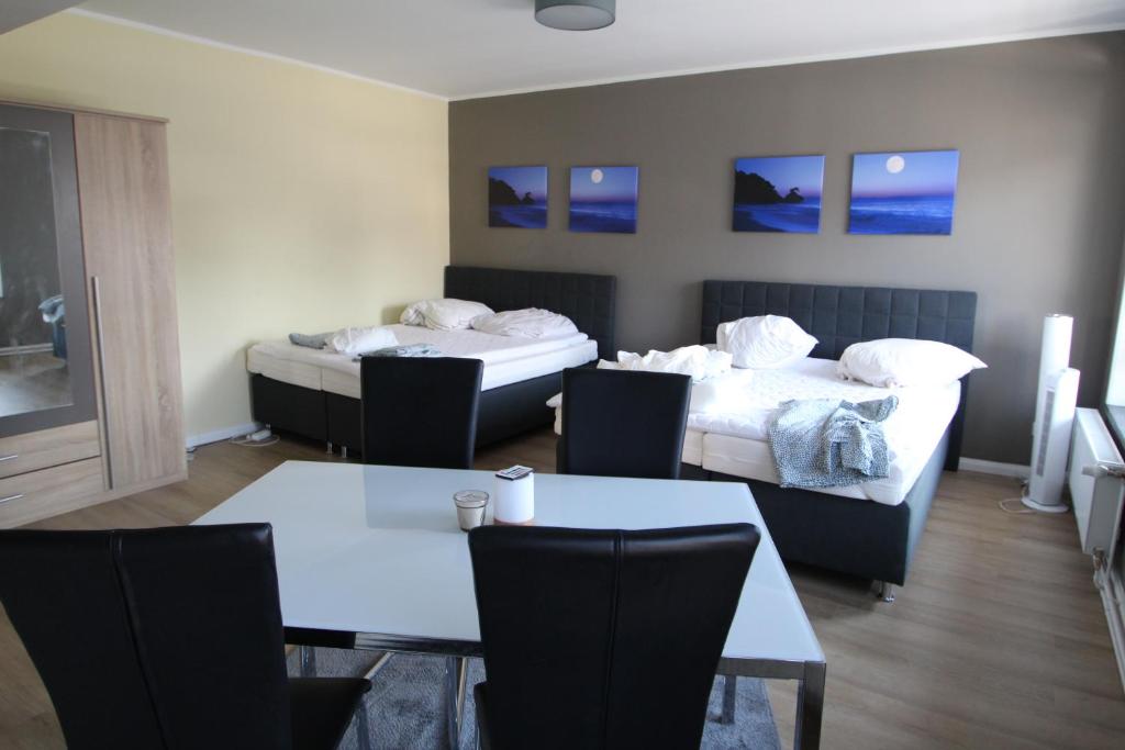 Cette chambre d'hôtel comprend deux lits, une table et des chaises. dans l'établissement Fackenburgerapartments, à Lübeck