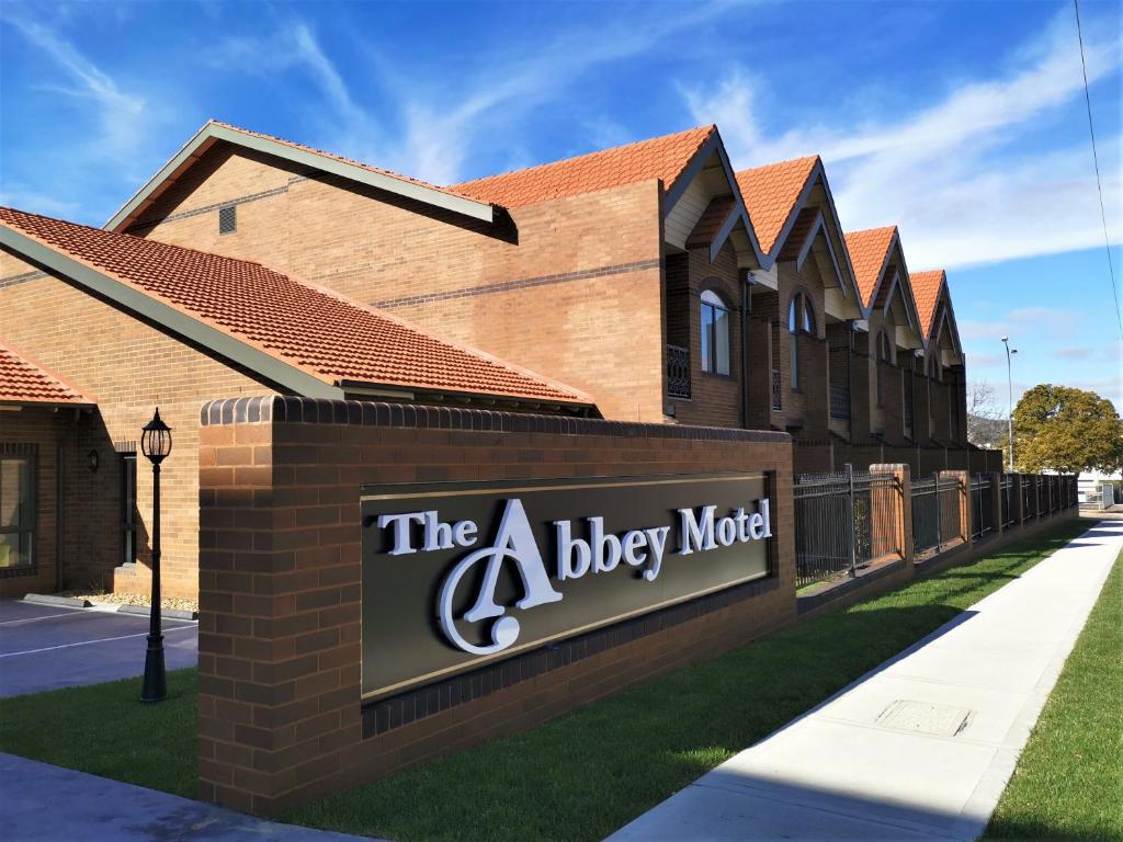 Un cartel que anuncia un motel para perros frente a un edificio. en The Abbey Motel Goulburn, en Goulburn