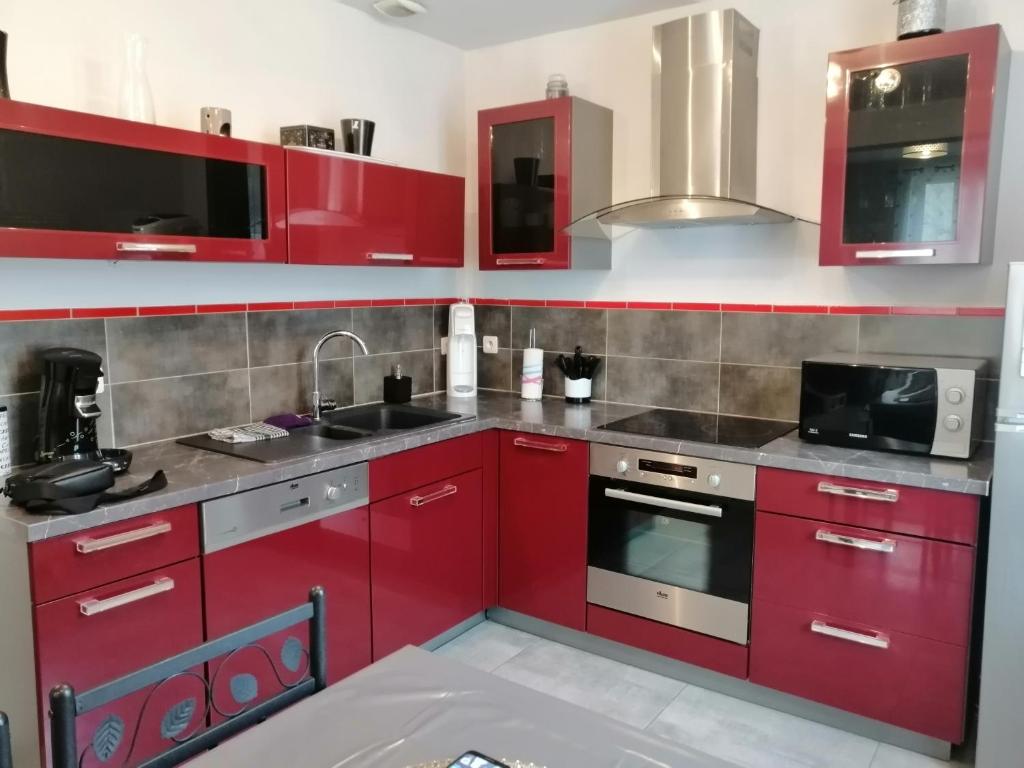 a kitchen with red cabinets and a sink at Résidence Lawawi prés de la gare au calme in Albertville
