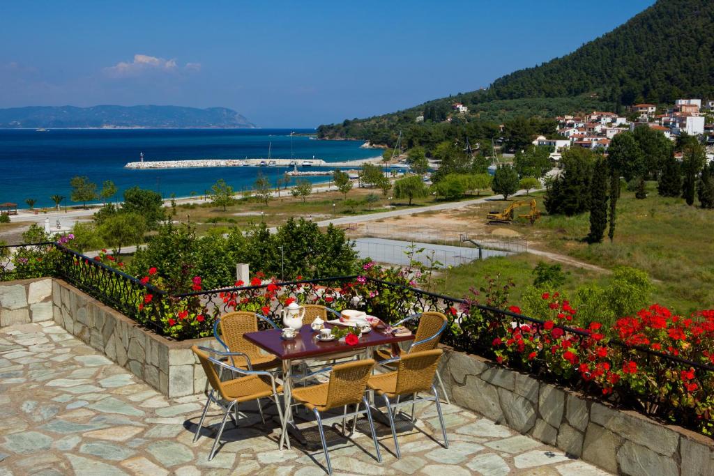 a table and chairs on a retaining wall with flowers at Hovolo Hotel Apartments in Neo Klima