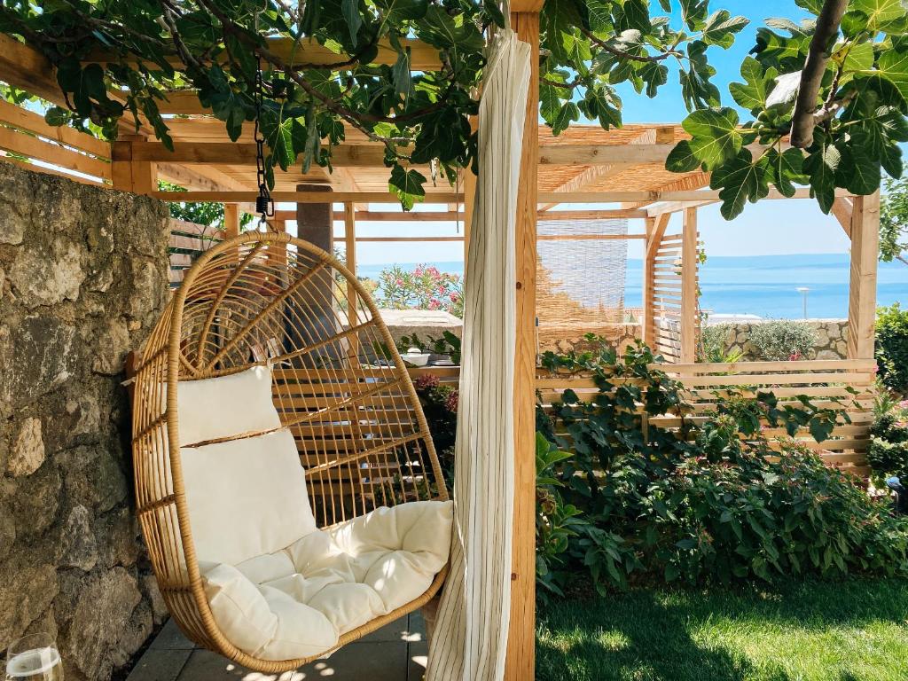 a wicker chair hanging under a pergola at Sunshine Residence in Stara Baška